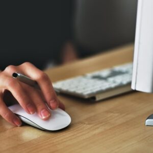 hand of a person holding a pen and using a computer mouse